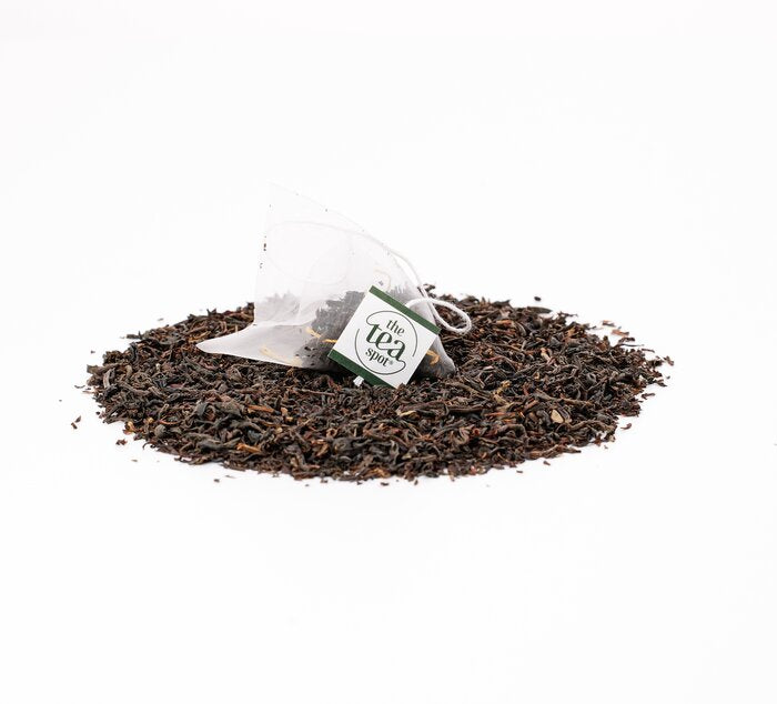 
                  
                    a tea bag filled with black tea sits on top of a pile of loose leaf black tea
                  
                