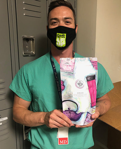 a doctor with a mask on holds a bag of tea