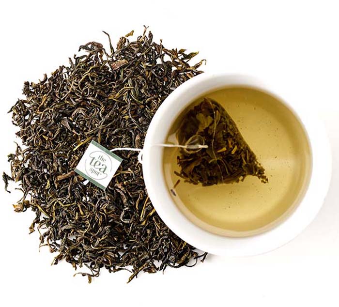 Organic Clouds and Mist tea bag Steeped in a tea cup and surrounded by loose leaf tea leaves