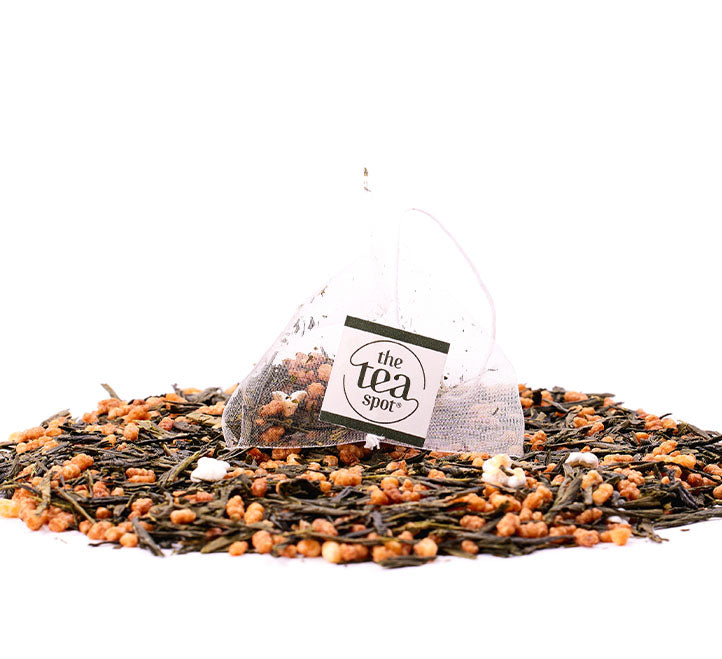 a tea bag with genmaicha in it sits on top of a pile of loose leaf genmaicha tea