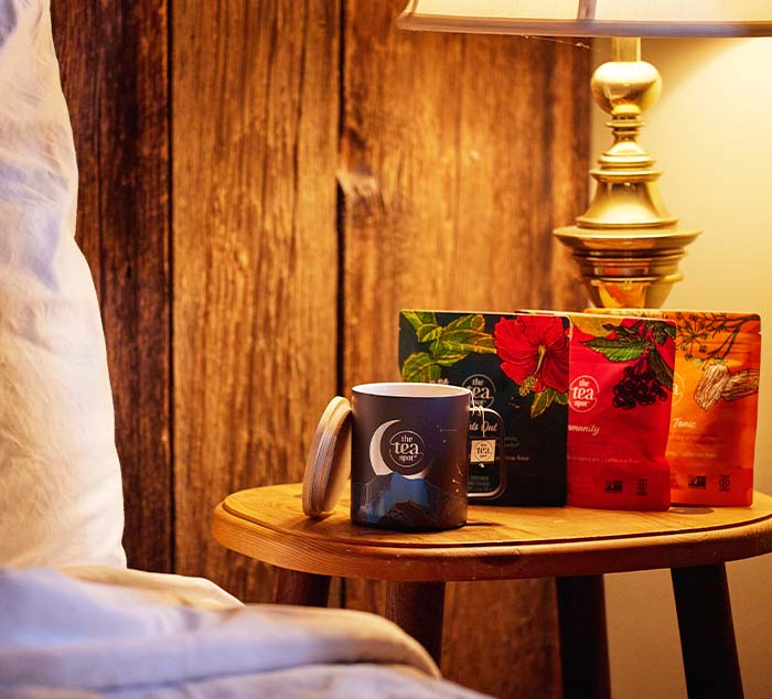 
                  
                    a camping tea mug sits next to a bed with three bags of tea
                  
                