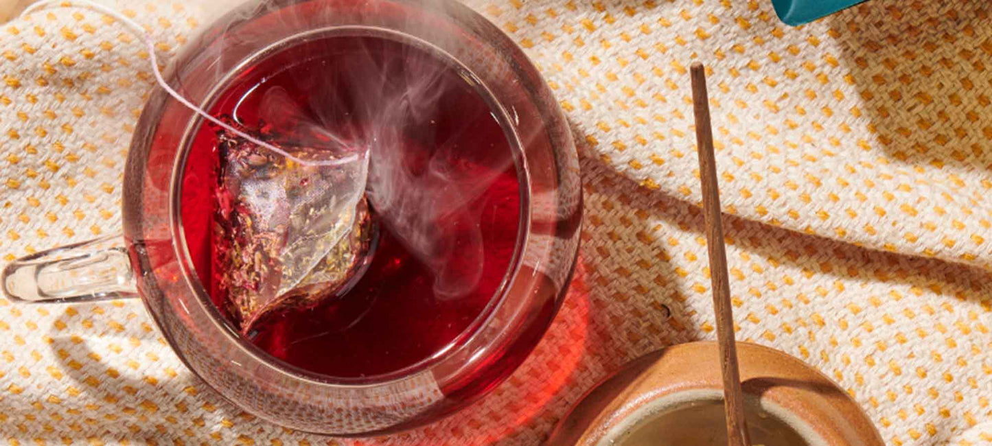 a teacup with hibiscus tea in it sits on a yellow tablecloth