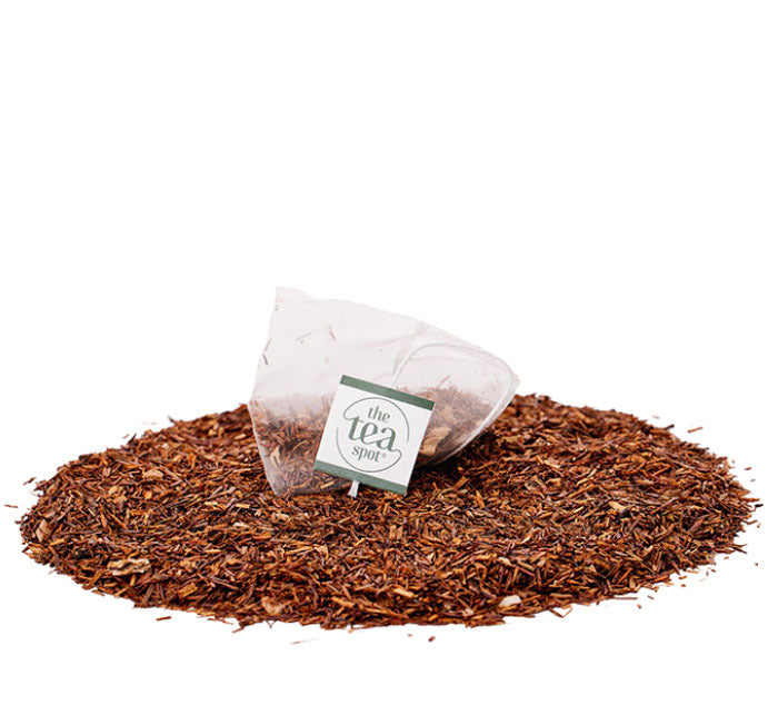 
                  
                    a tea bag filled with herbal rooibos tea sits on top of a pile of loose leaf herbal tea
                  
                
