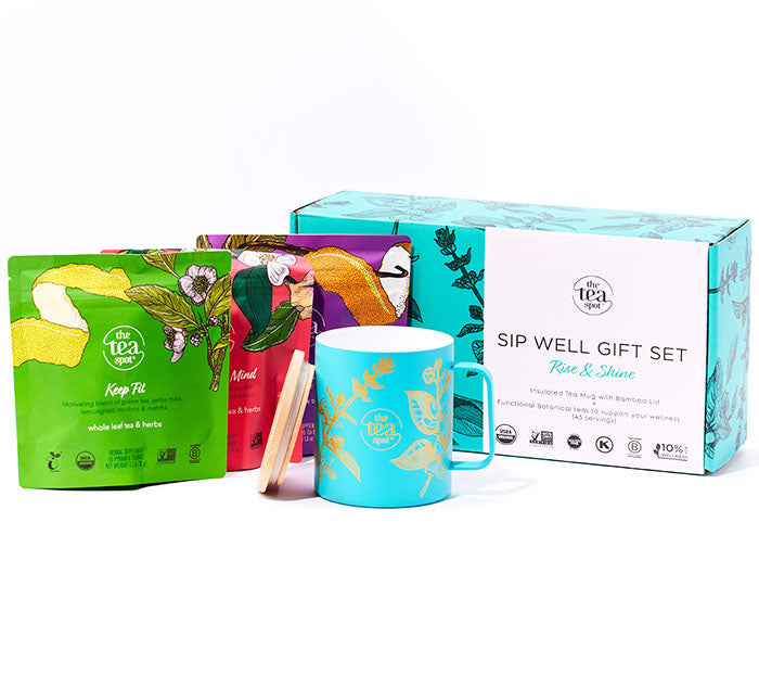a box that says sip well gift set sits next to three bags or tea, and a teal mug with gold designs sits in front