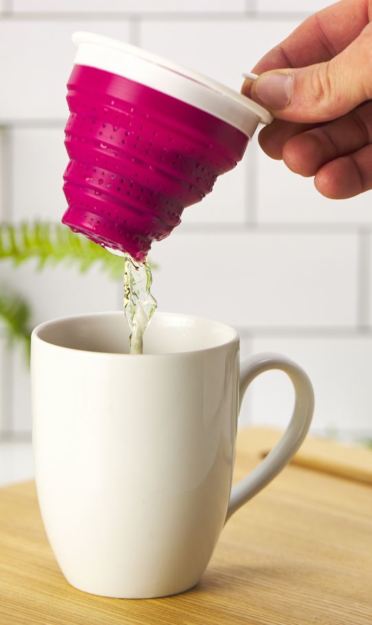 a tea infuser is lifted out of a tea cup