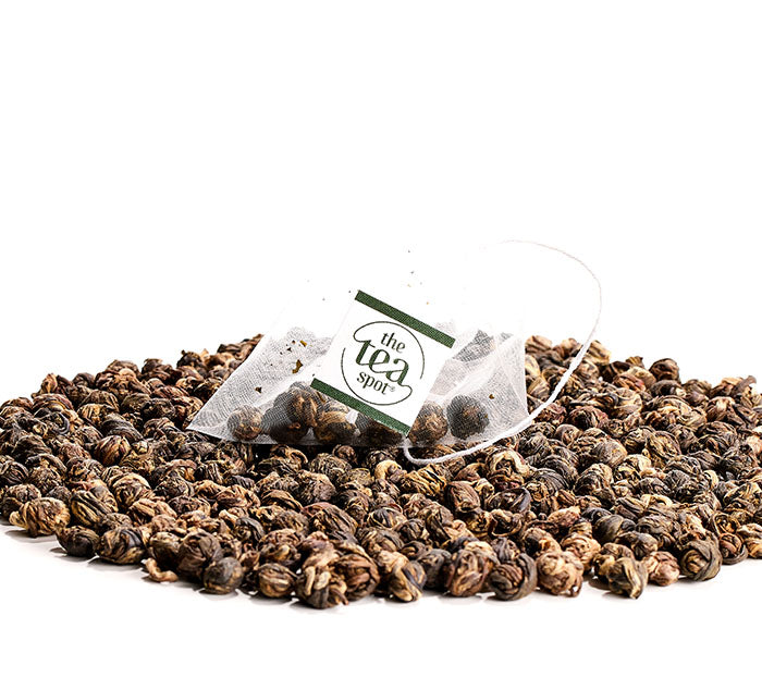 
                  
                    a pile of jasmine pearls tea with a tea bag with jasmine pearls green tea on top
                  
                
