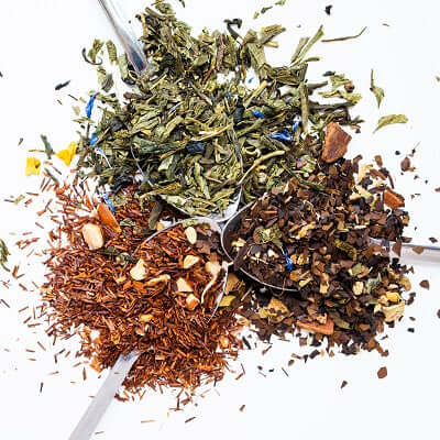 three spoons with loose leaf tea sit on a white surface