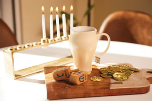 a tea mug sits in front of a menorah 