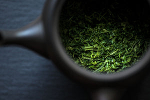 a tea pot is open showing green tea leaves inside