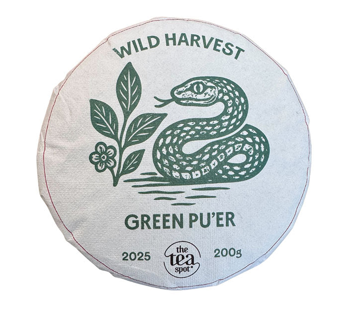 Round package of 2025 Wild Harvest Green Pu'er tea with snake and leaf design on a white background
