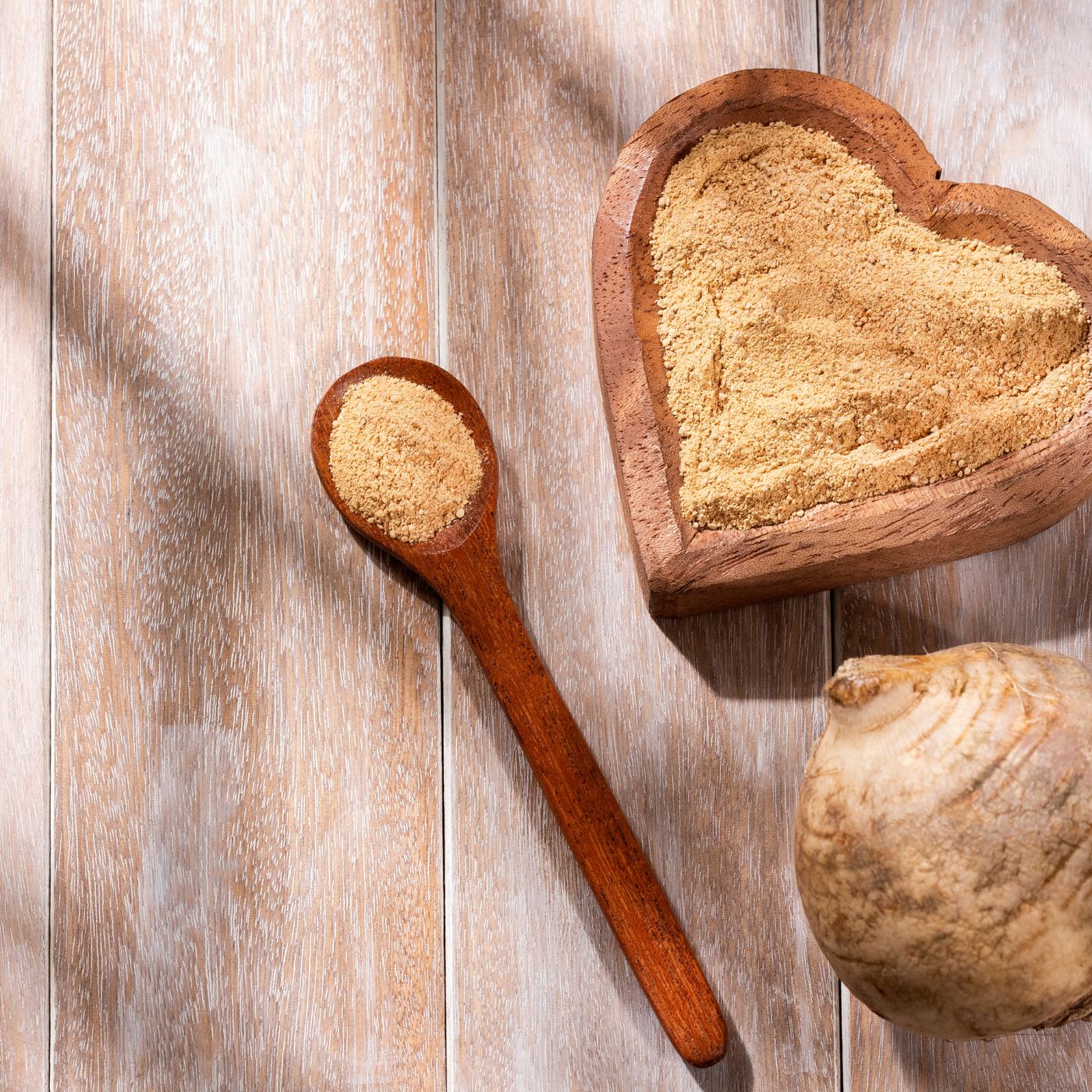 maca root sitting next to a heart shaped bowl with maca root powder