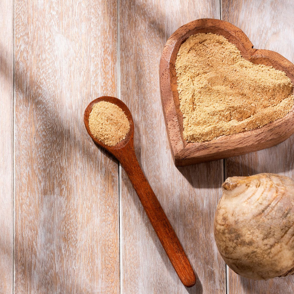 maca root sitting next to a heart shaped bowl with maca root powder
