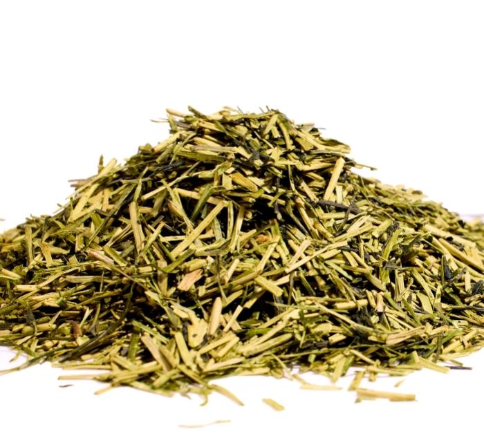 Pile of kukicha loose leaf tea on a white background