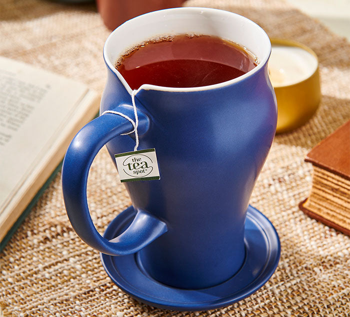 
                  
                    a mug sits on a table surrounded by books. There is a tea bag in the mug as well as brewed tea
                  
                