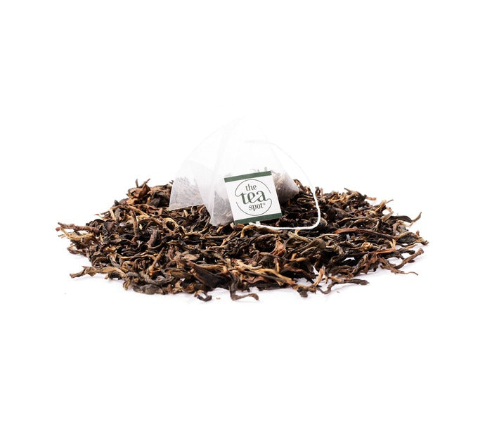 
                  
                    yunnan black tea in a tea bag sits on top of yunnan loose leaf tea
                  
                