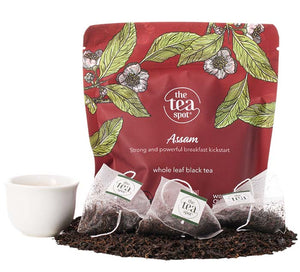 a bag reading Assam sits behind a pile of loose leaf black tea and assam tea bags