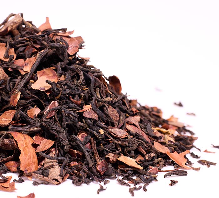 Heap of bitaco cacao black tea leaves with cacao husks on a white background