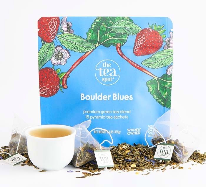 Tea package for 'Boulder Blues' tea with a cup of tea and loose tea leaves on a white background.