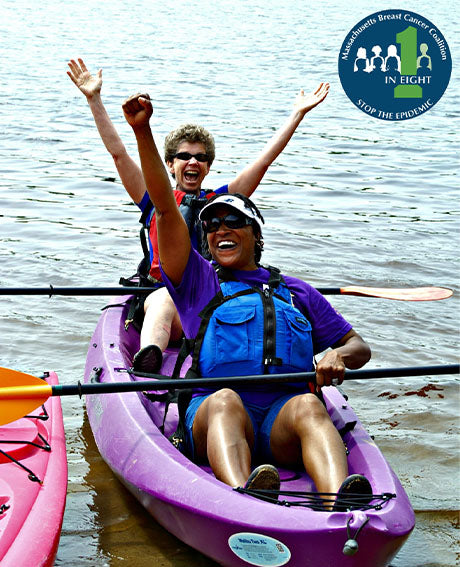 two women smile and wave from a kayak