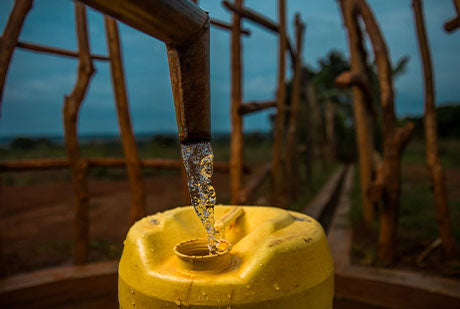 a pipe pours clean water into a yellow jug