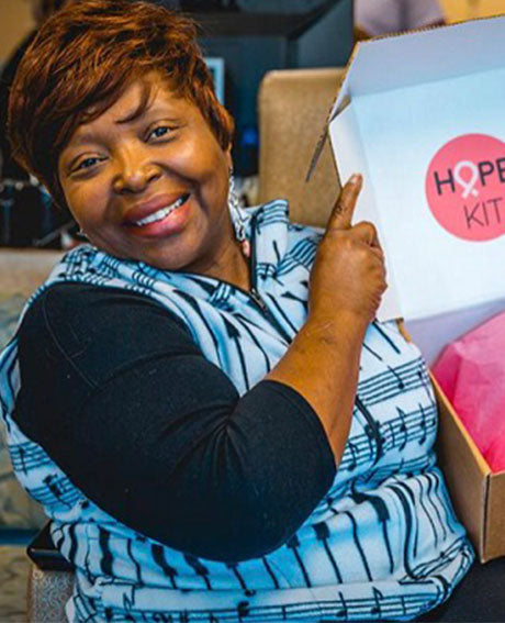 a woman smiles holding open a box that reads hope kit