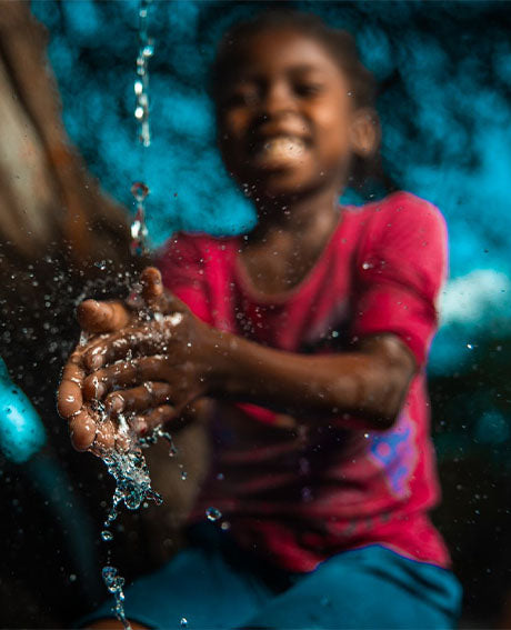 a girl washes her hands in clean water