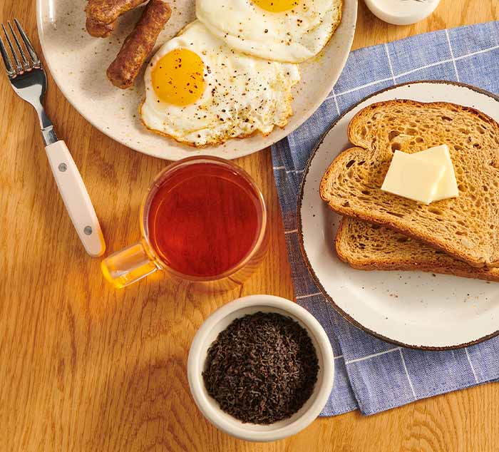 
                  
                    Breakfast setting with eggs, toast, and tea on a wooden table.
                  
                