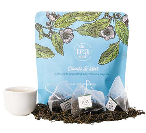 a bag reading Clouds and Mist uplifting yet grounding daily immune support behind tea bags and tea leaves and a tea cup