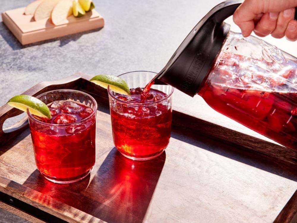 a pitcher pours cold brewed tea into two glasses