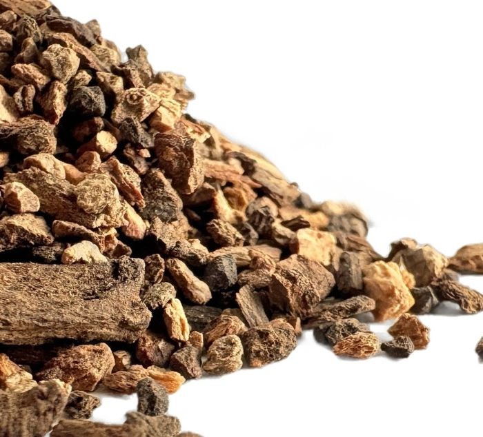 A pile of dried, chopped brown roasted dandelion root tea photographed on a clean white background.