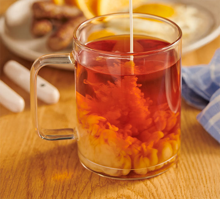 milk is being poured into a cup of english breakfast tea