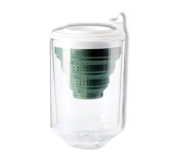 a double walled glass tea cup with a green tea steeper in it