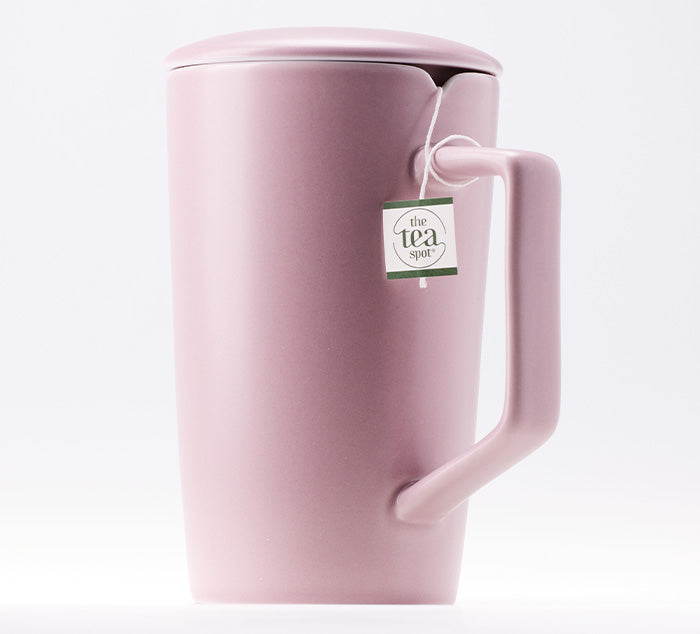 a light pink ceramic tea mug with a notch for a tea bag that is wrapped around the handle