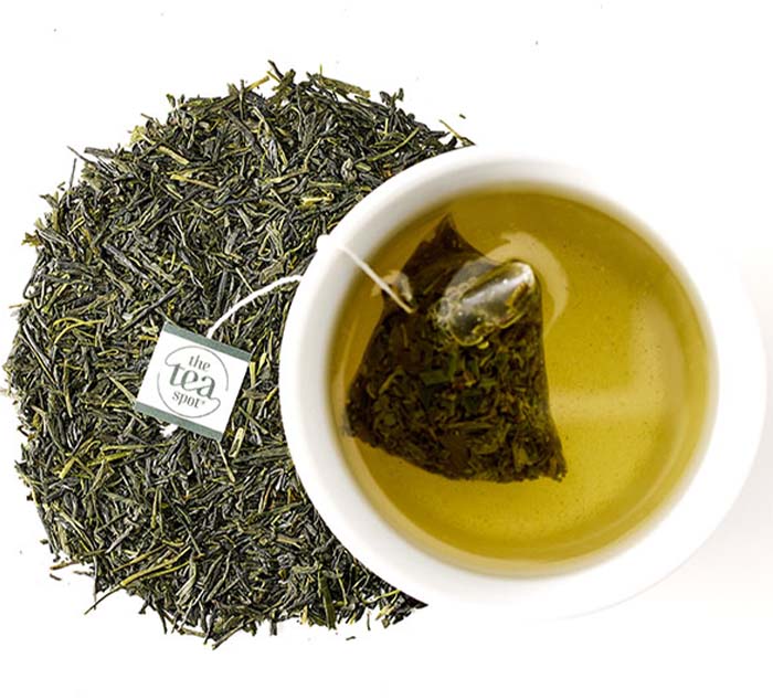
                  
                    a tea bag of green tea steeps in a cup surrounded by loose leaf tea
                  
                