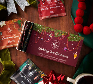a box reading holiday tea collection is open on a table with christmas decorations and three holiday tea bags