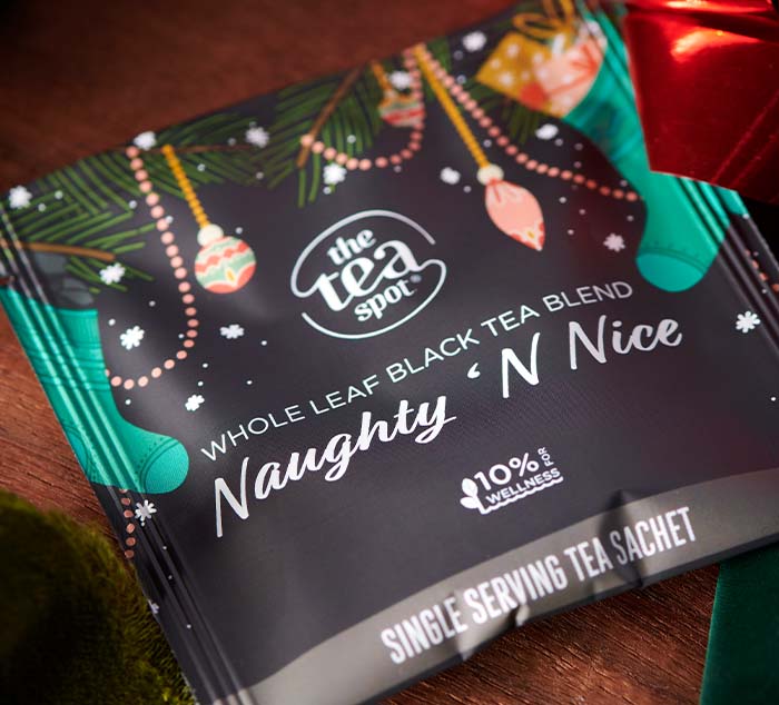 
                  
                    a black tea bag wrapper reading naughty 'n nice sits on a table with christmas decorations
                  
                
