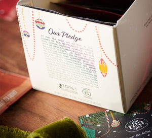a box with holiday tea bags in it reads "our pledge" surrounded by christmas teas