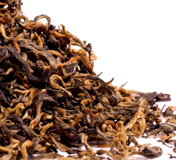 Close-up of dried Kumari Gold tea leaves on a white background