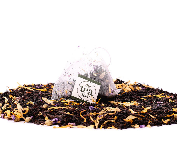 a tea bag with black mango tea sits on top of a pile of loose leaf mango black tea