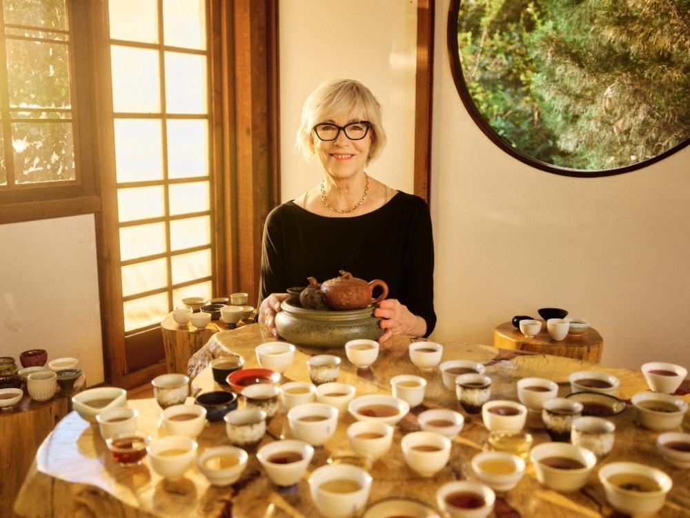 a person sits behind 100 cups of tea