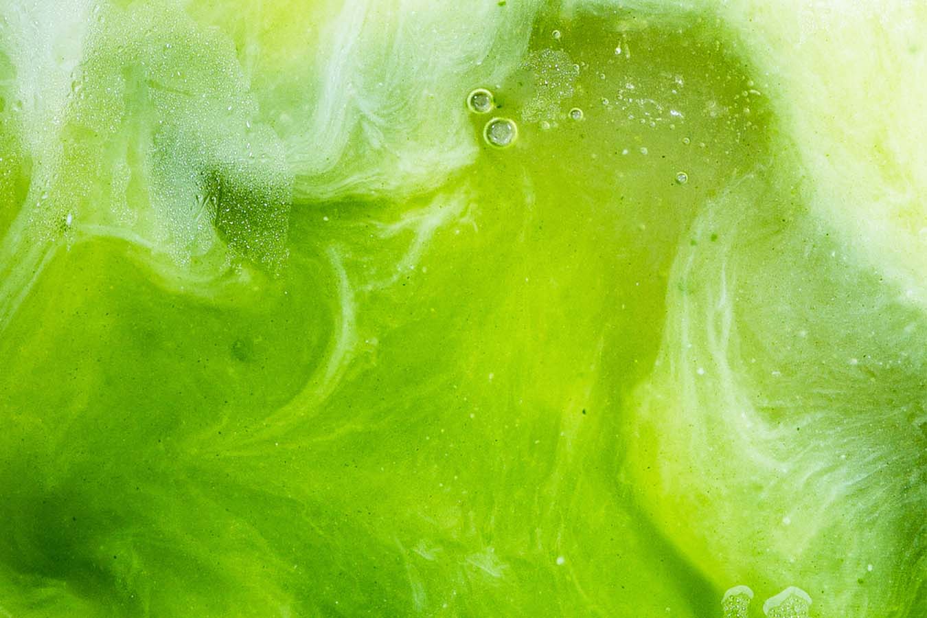 matcha tea is swirled with milk in an up close shot
