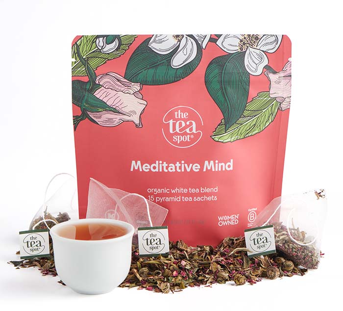 Tea packaging with 'Meditative Mind' label, cup of tea, and tea leaves on a white background