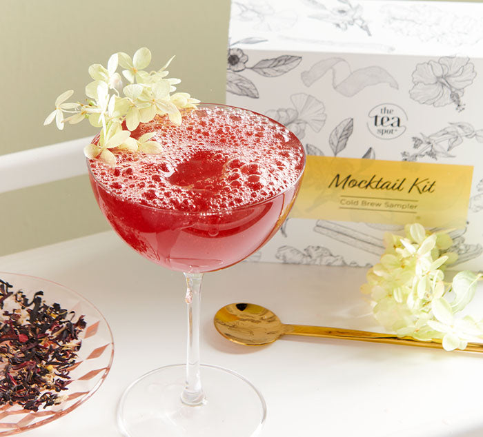 
                  
                    a red tea mocktail with a flower in it sits in front of a box reading mocktail kit 
                  
                