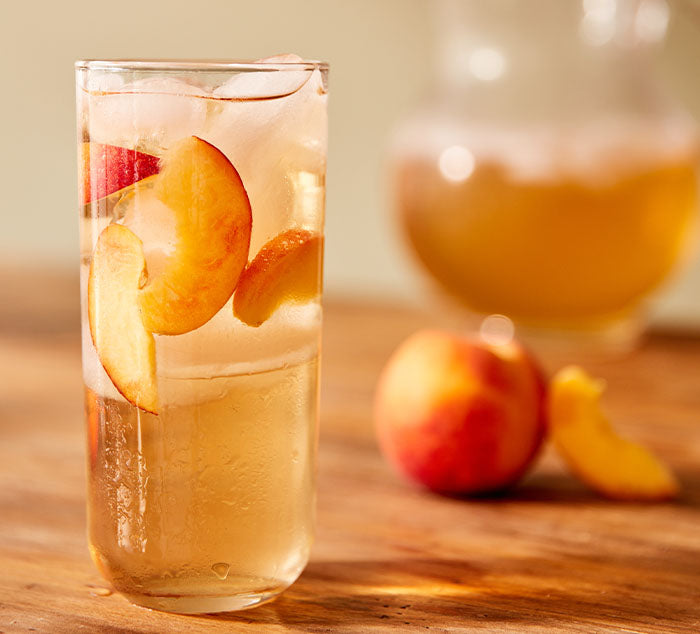 
                  
                    iced peach oolong tea sits on a glass on a wooden table
                  
                