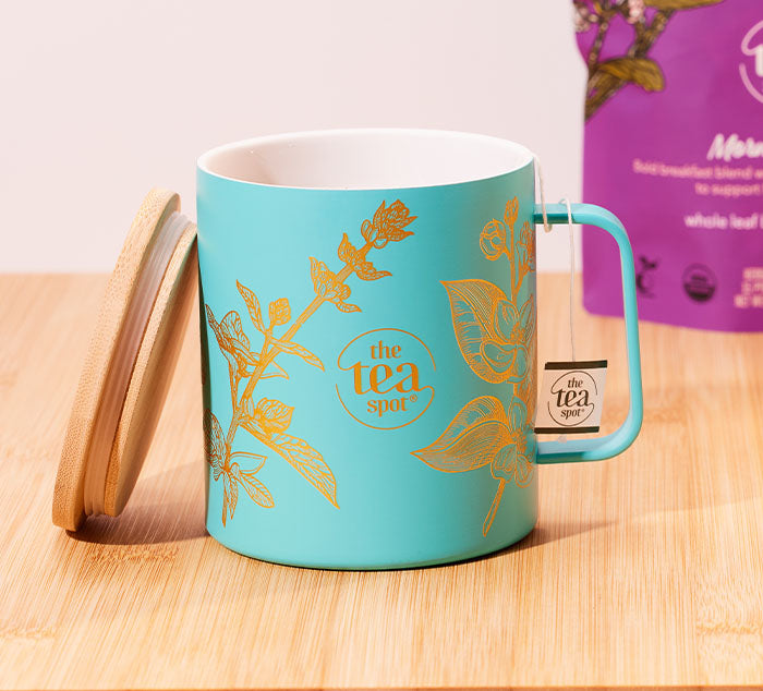 
                  
                    a teal mug with gold designs has a tea bag string wrapped around its handle
                  
                
