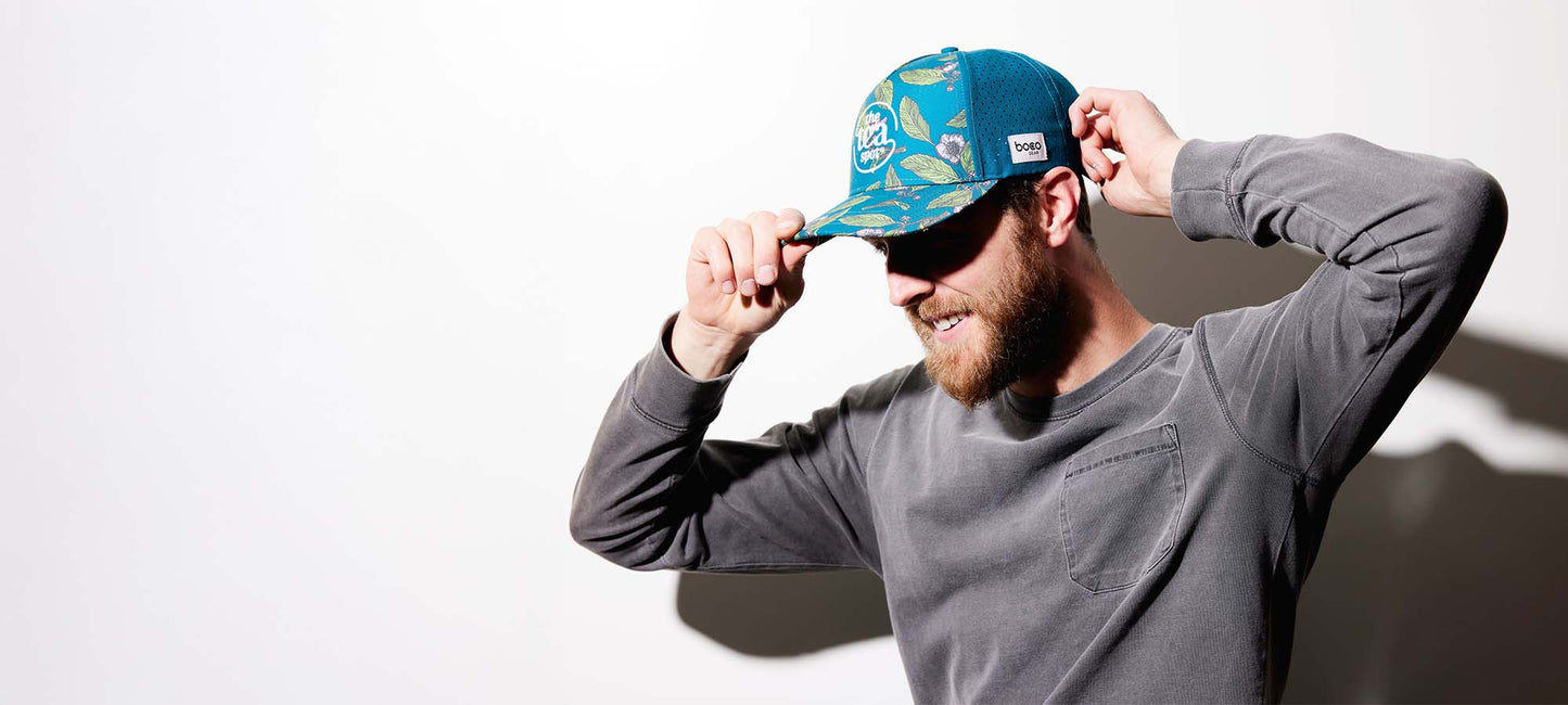 a man is wearing a teal hat that says the tea spot and smiling