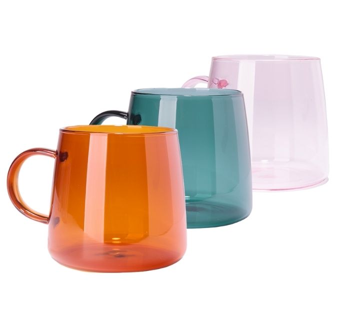 three colored glass tea mugs in a row. orange, teal, and light pink