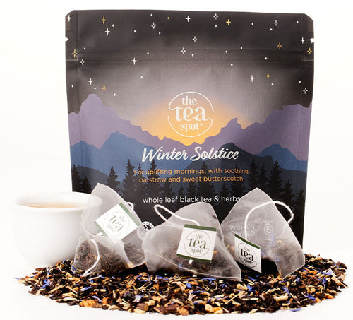 a bag reading winter solstice, for uplifting mornings, with soothing oatstraw and butterscotch has tea bags and loose leaf tea in front of it