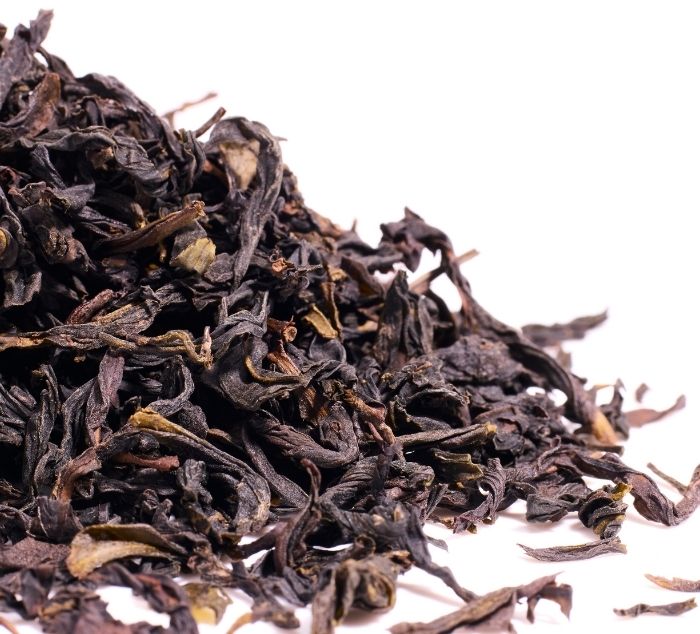 Close-up of dried ya shi xiang tea leaves on a white background