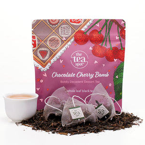 a bag reads chocolate cherry bomb with three tea bags sitting in front of it on a pile of loose leaf tea
